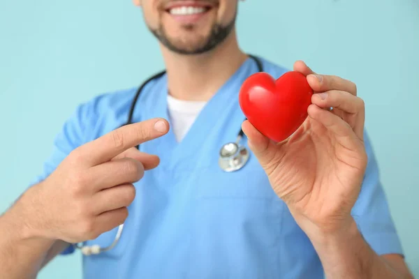 Férfi kardiológus piros szív a színes háttér, közelkép — Stock Fotó