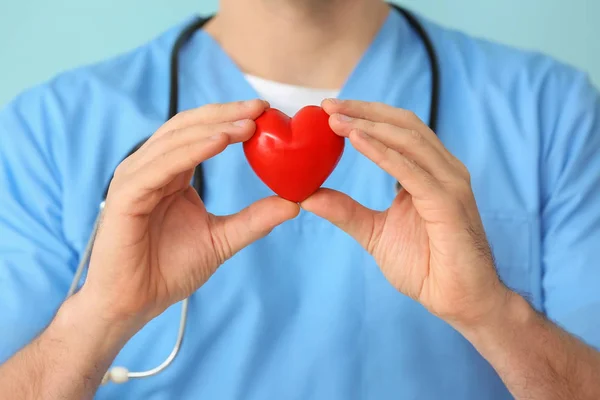 Male cardiologist with red heart on color background, closeup — Stock Photo, Image