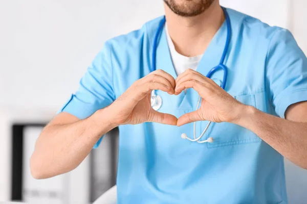 Mannelijke cardioloog maakt hart met zijn handen in de kliniek — Stockfoto