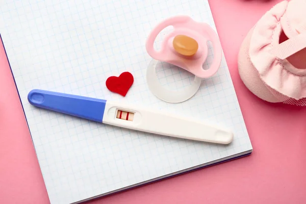 Pregnancy test, notebook and pacifier on color background — Stock Photo, Image