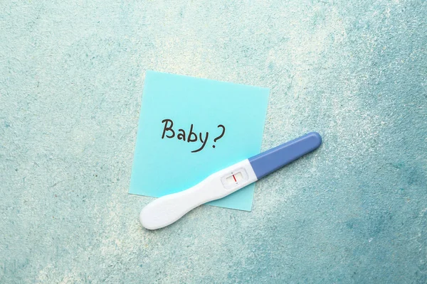 Pregnancy tests and paper with text BABY? on color background