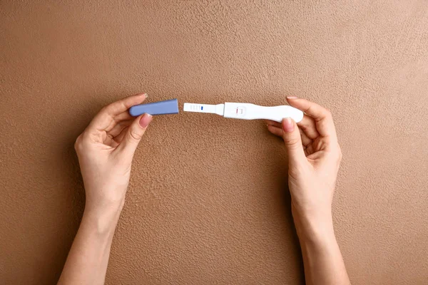 Female hands with pregnancy test on color background — Stock Photo, Image