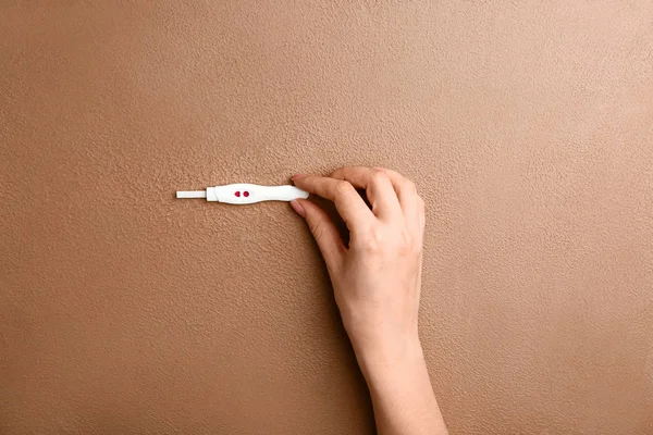 Женская рука с тестом на беременность на цветном фоне — стоковое фото