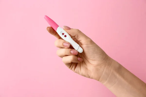 Weibliche Hand mit Schwangerschaftstest auf farbigem Hintergrund — Stockfoto