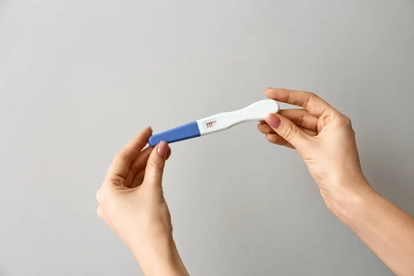 Female hands with pregnancy test on grey background — Stock Photo, Image