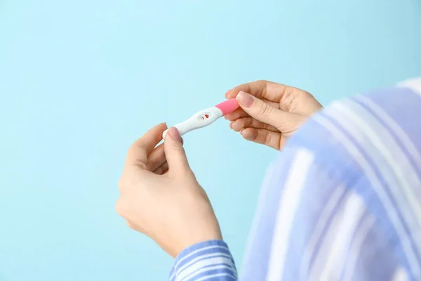 Mujer joven con prueba de embarazo sobre fondo de color — Foto de Stock