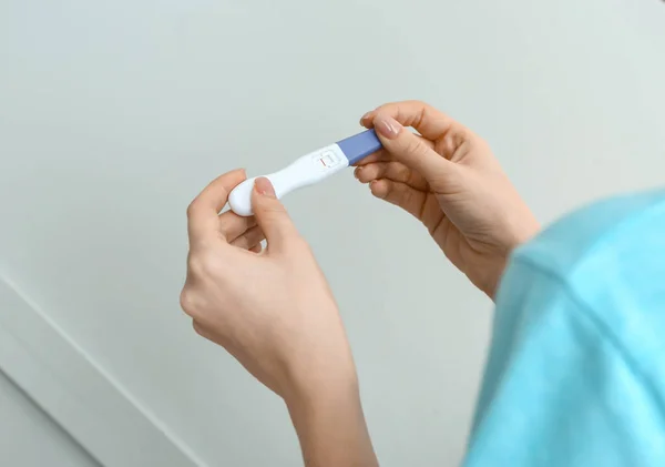 Young woman with pregnancy test on grey background — Stock Photo, Image