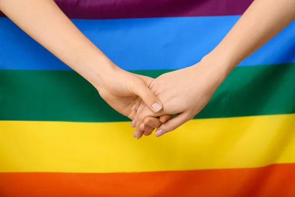 Kobiety trzymające się za ręce przy tęczowej fladze. Koncepcja LGBT — Zdjęcie stockowe
