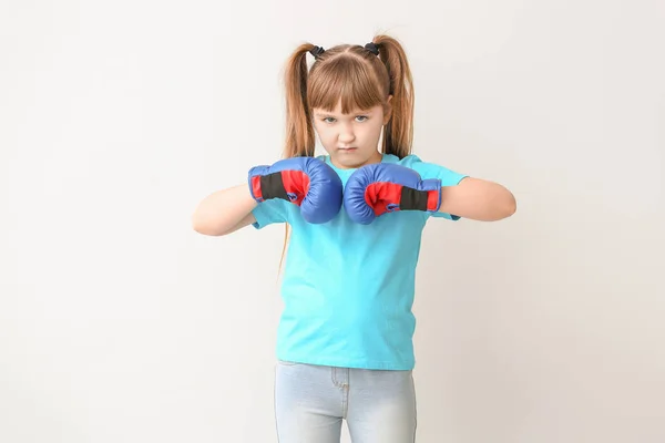 Kleines Mädchen in Boxhandschuhen auf hellem Hintergrund. Konzept des Feminismus — Stockfoto