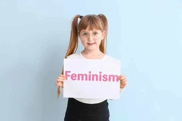 Klein meisje met papier met woord feminisme op kleur achtergrond — Stockfoto