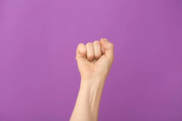 Hand kvinna med knuten knytnäve på färg bakgrund — Stockfoto