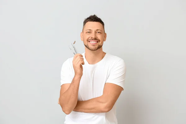 Hombre con herramientas dentales sobre fondo claro — Foto de Stock