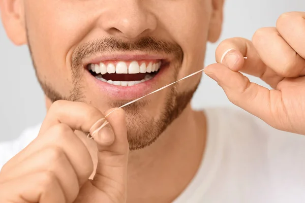 Handsome man flossing teeth on grey background, closeup — Stock Photo, Image