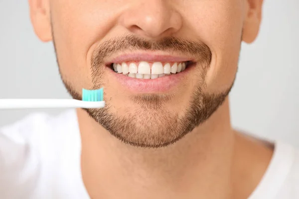 Handsome man with tooth brush on grey background, closeup — Stock Photo, Image