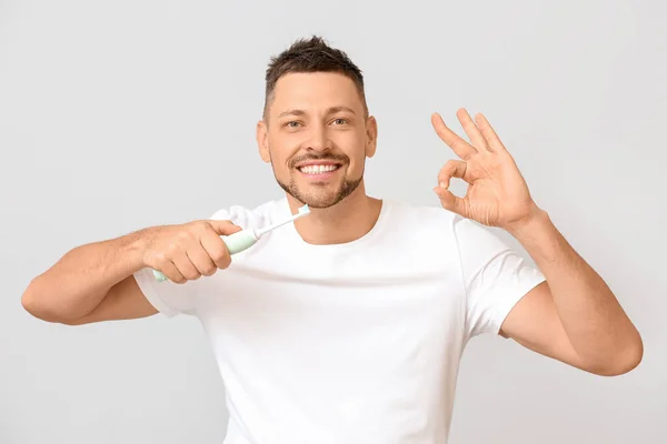 Bonito homem com escova de dentes mostrando OK no fundo cinza — Fotografia de Stock