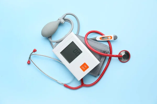 Elektronisches Blutdruckmessgerät und Thermometer auf farbigem Hintergrund — Stockfoto