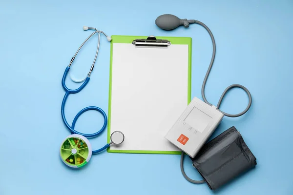 Clipboard, sphygmomanometer and pills on color background — 스톡 사진