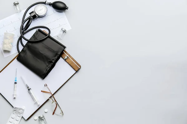 Composition with sphygmomanometer, clipboard and pills on light background — Stock Photo, Image