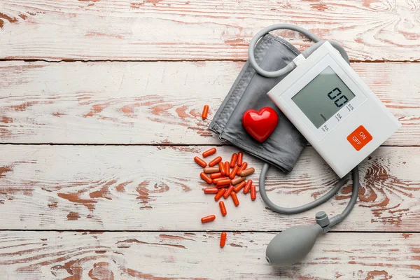 Blutdruckmessgerät und Pillen auf Holzgrund — Stockfoto
