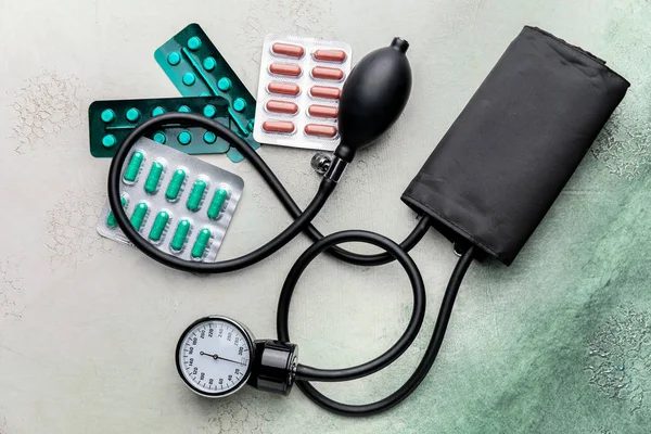 Pills and sphygmomanometer on color background — Stock Photo, Image