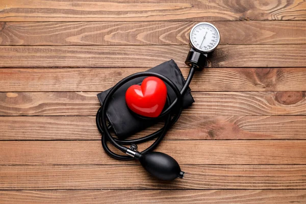 Sphygmomanometer and red heart on wooden background — Stock Photo, Image