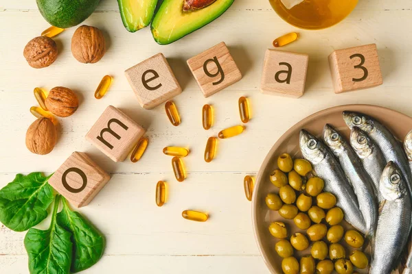 Wooden cubes, healthy products with high omega 3 and fish oil pills on white table — Stock Photo, Image