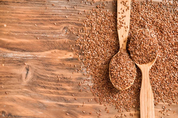 Spoons with flax seeds on wooden background — Stock Photo, Image