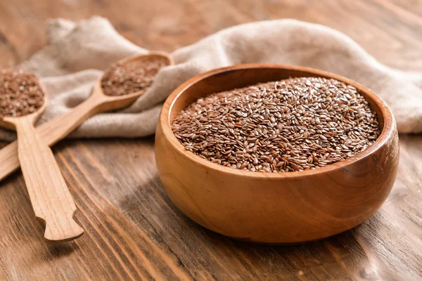 Bowl with flax seeds and spoons on wooden background — Stock Photo, Image