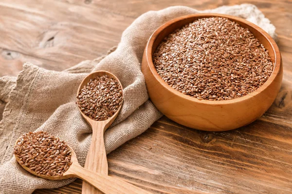 Bowl with flax seeds and spoons on wooden background — Stock Photo, Image
