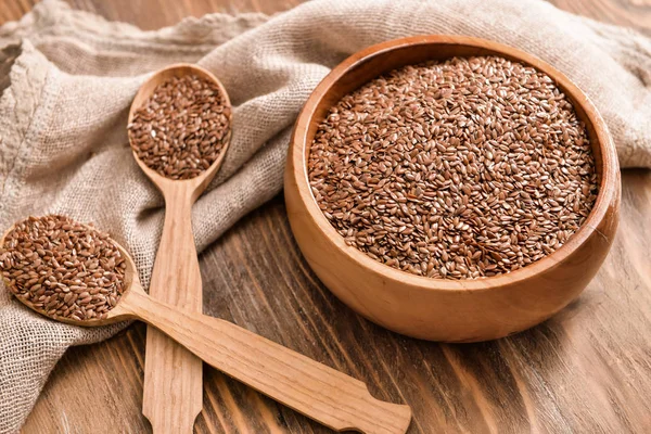 Bowl with flax seeds and spoons on wooden background — Stock Photo, Image