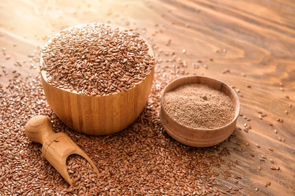 Bowls with flax seeds, powder and scoop on wooden background — Stock Photo, Image