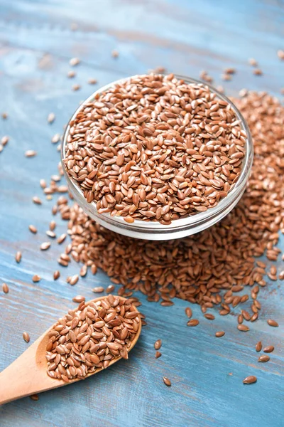 Bowl with flax seeds and spoon on wooden background — Stock Photo, Image