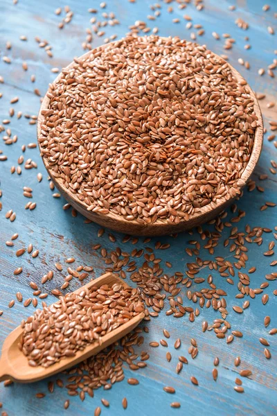 Bowl with flax seeds and scoop on wooden background — Stock Photo, Image