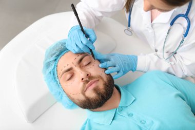 Klinikte hastanın yüzüne işaret uygulayan plastik cerrah