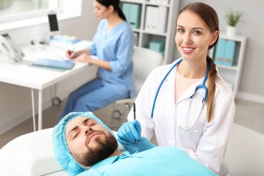 Klinikte hastanın yüzüne işaret uygulayan plastik cerrah