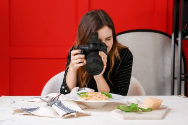 Genç bir kadın profesyonel stüdyoda makarna fotoğrafı çekiyor.
