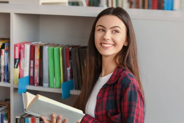 Kütüphanede sınava hazırlanırken kitap okuyan kız öğrenci