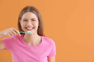 Arka planda diş fırçası ve macunu olan güzel genç bir kadın.