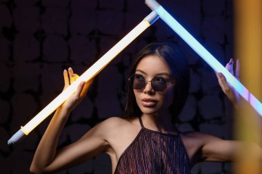 Koyu arkaplanda neon lambaları olan güzel bir kadının tonlu portresi.