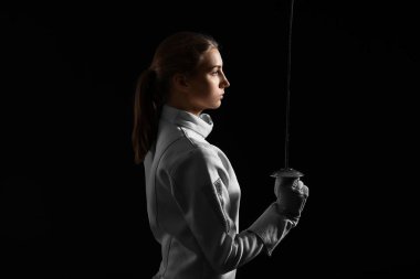 Koyu arka plan üzerinde genç kadın fencer