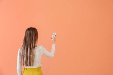 Renk arkaplanı üzerinde klima uzaktan kumandalı genç kadın