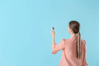 Renk arkaplanı üzerinde klima uzaktan kumandalı genç kadın