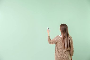 Renk arkaplanı üzerinde klima uzaktan kumandalı genç kadın