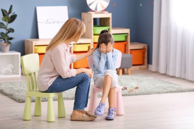 İçeride üzgün küçük bir kızla çalışan bir psikolog.