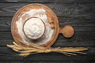 Koyu ahşap arka planda un ve yemek kasesi.