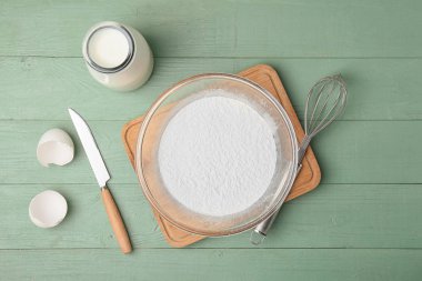 Tahta arka planda buğday unu, yumurta ve süt ile kase