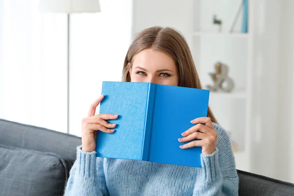 Vacker ung kvinna läser bok hemma — Stockfoto