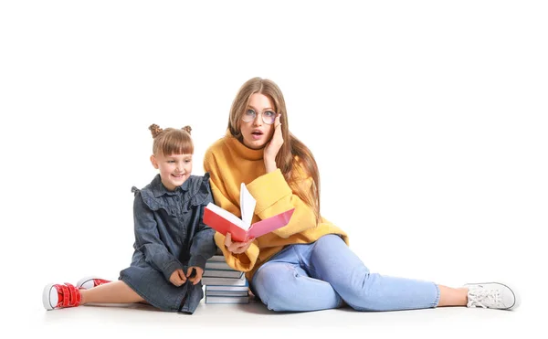 Vacker ung kvinna och hennes lilla dotter läser böcker på vit bakgrund — Stockfoto