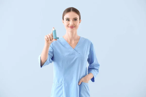 Portrait of female doctor with inhaler on light background — Stock Photo, Image