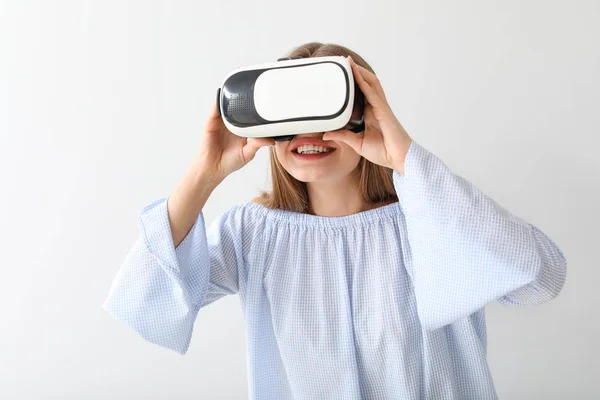 Junge Frau mit Virtual-Reality-Brille auf hellem Hintergrund — Stockfoto